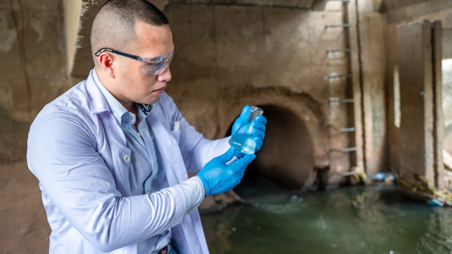 Científico ambiental tomando muestra de agua para analítica acreditada de vertido industrial