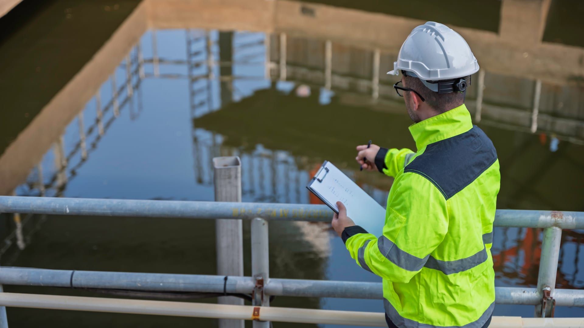 Técnico industrial revisando datos de autorización de vertido en planta de tratamiento de aguas residuales