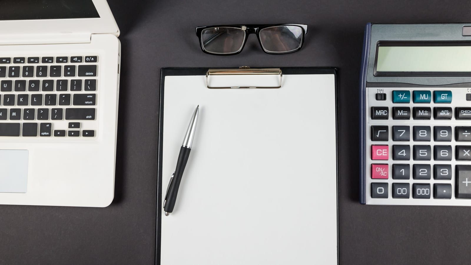 Calculadora con cuaderno y bolígrafo sobre mesa, simbolizando el cálculo del canon de control de vertidos