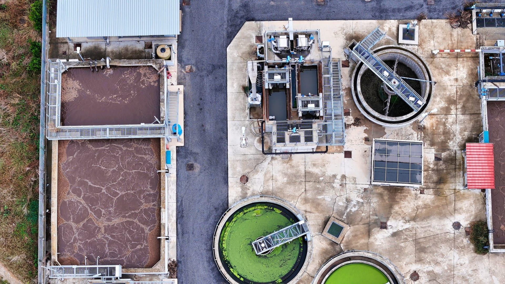 Vista aérea de una planta industrial de tratamiento de aguas residuales con tanques de aireación y decantación
